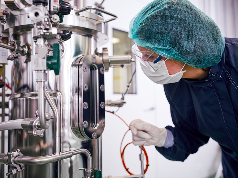 Scientist with a fermenter for biopharmaceutical production in the Life Science industry Fermenter and scientist in biopharmaceutical manufacturing