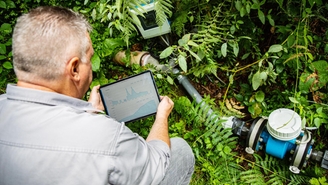 Man with flowmeter and tablet at a spring discharge