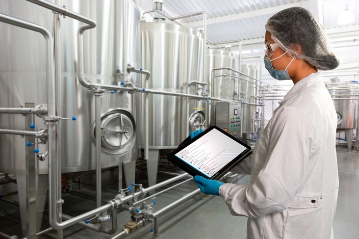 Mitarbeiterin vor einer Produktionsanlage in der Lebensmittel- 
industrie und prüft den Netilion Asset Health Status