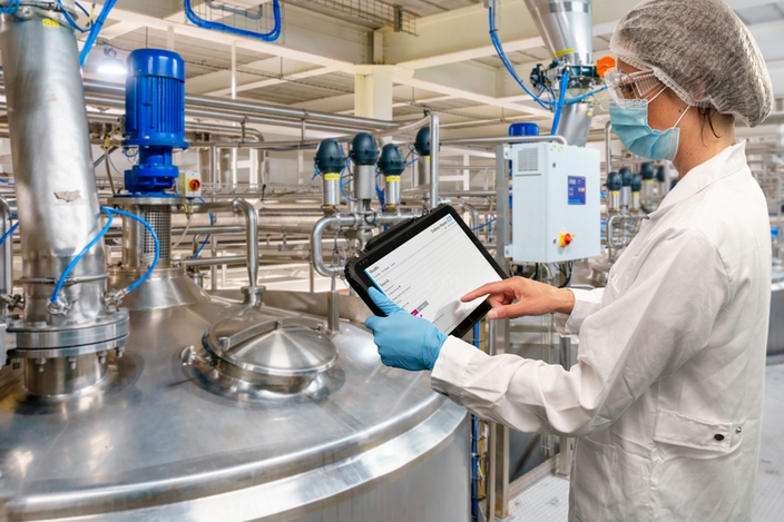 Woman standing in production facility and checking the Netilion Asset Health status